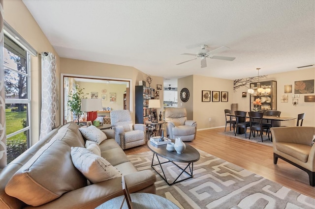 living room featuring a textured ceiling, light wood-type flooring, and ceiling fan