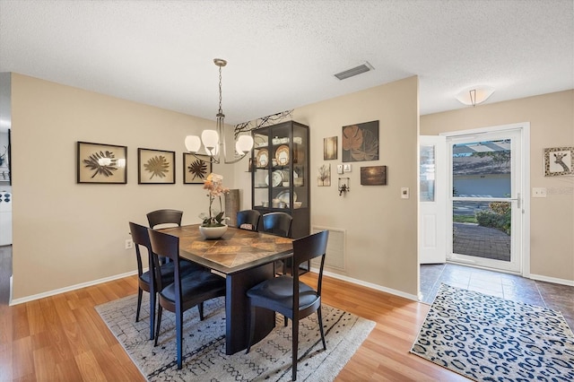 dining space featuring a textured ceiling, a notable chandelier, and hardwood / wood-style flooring