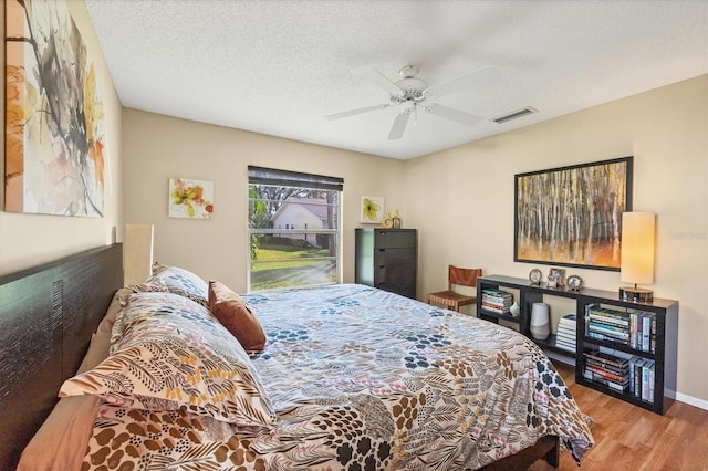 bedroom featuring ceiling fan, light hardwood / wood-style floors, and a textured ceiling