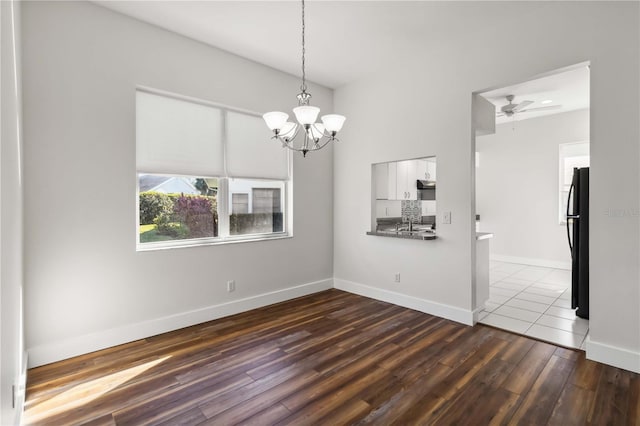 unfurnished room with ceiling fan with notable chandelier and dark hardwood / wood-style floors