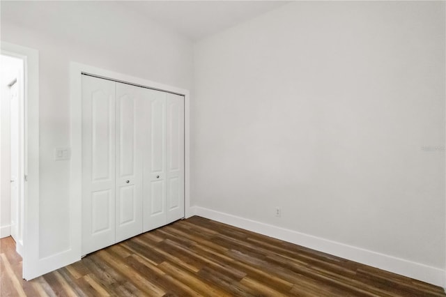 unfurnished bedroom featuring a closet and dark wood-type flooring