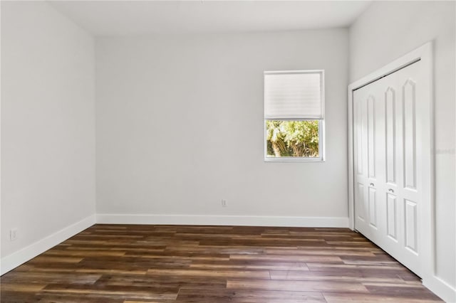 unfurnished bedroom with a closet and dark wood-type flooring