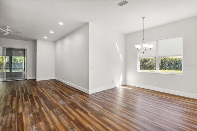 spare room with dark hardwood / wood-style floors and ceiling fan with notable chandelier