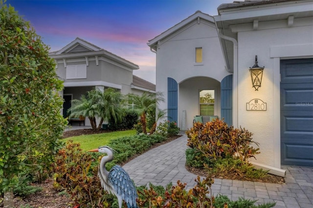 doorway to property featuring an attached garage and stucco siding