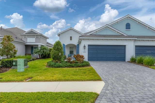 view of front facade with a garage, decorative driveway, a front yard, and stucco siding