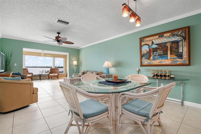 dining area with ceiling fan, light tile patterned floors, ornamental molding, and a textured ceiling