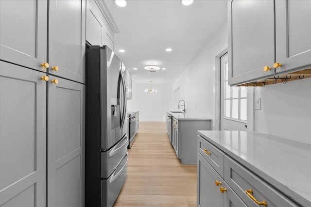 kitchen with appliances with stainless steel finishes, light stone counters, gray cabinetry, and sink