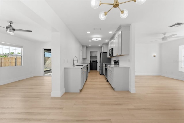 kitchen featuring stainless steel appliances, ceiling fan with notable chandelier, and light hardwood / wood-style floors