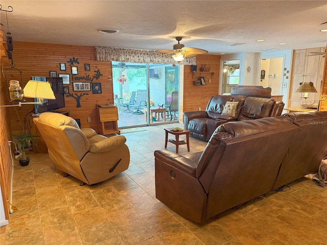 living room featuring ceiling fan and wooden walls