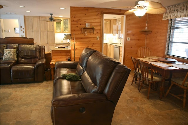 living room with wooden walls, sink, and ceiling fan