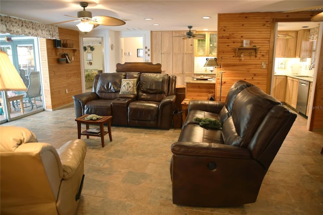 living room featuring sink, ceiling fan, and wood walls