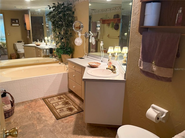 bathroom featuring vanity, tiled bath, and toilet