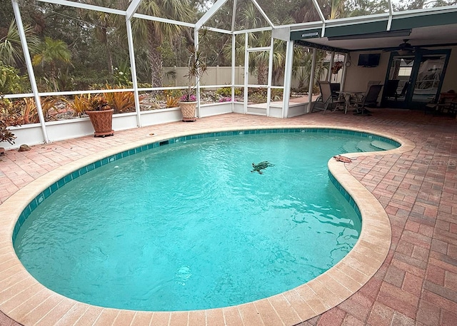 view of swimming pool with a patio, glass enclosure, and ceiling fan