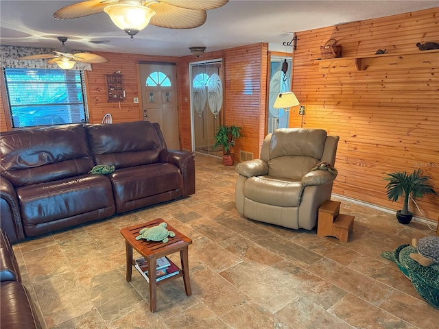 living room featuring ceiling fan and wooden walls