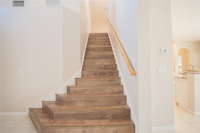 staircase featuring tile patterned floors and sink