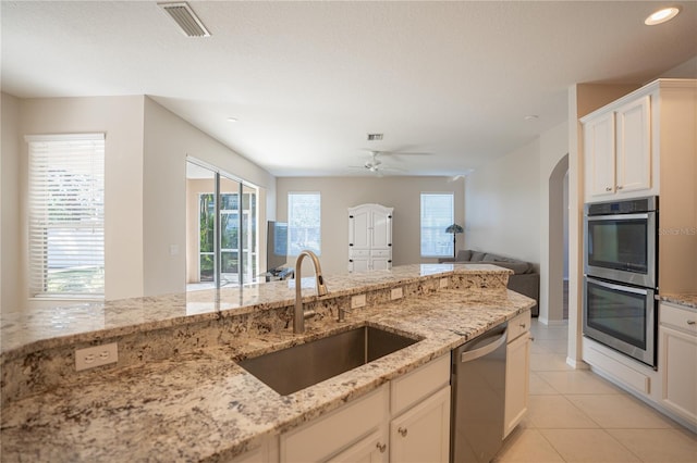 kitchen featuring sink, ceiling fan, light tile patterned floors, light stone countertops, and appliances with stainless steel finishes