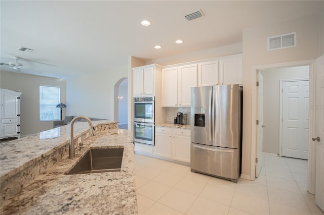 kitchen featuring white cabinets, sink, ceiling fan, appliances with stainless steel finishes, and light stone counters