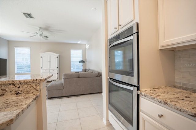 kitchen with light stone countertops, light tile patterned floors, backsplash, and plenty of natural light