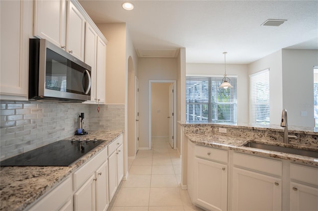 kitchen featuring sink, light tile patterned floors, backsplash, black electric stovetop, and white cabinets