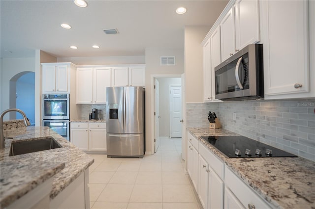 kitchen with light stone counters, white cabinetry, stainless steel appliances, and light tile patterned floors