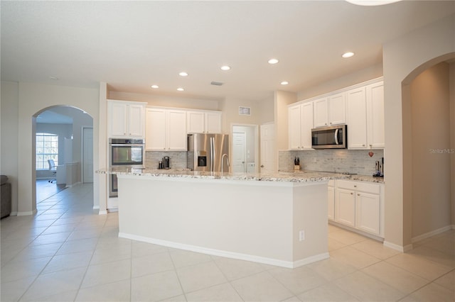 kitchen featuring white cabinets, stainless steel appliances, and an island with sink