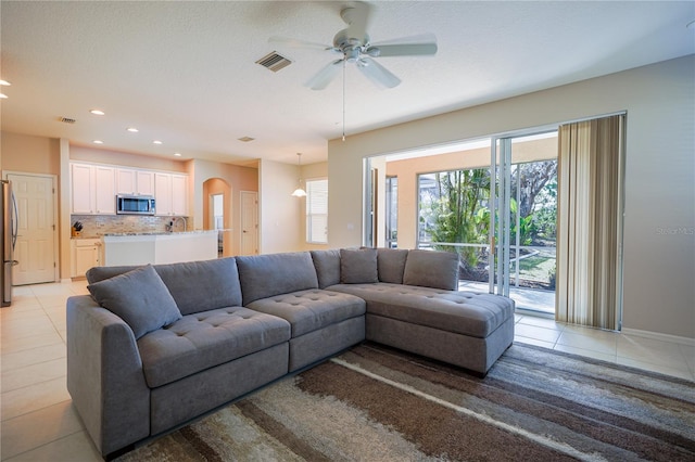 tiled living room featuring ceiling fan and sink