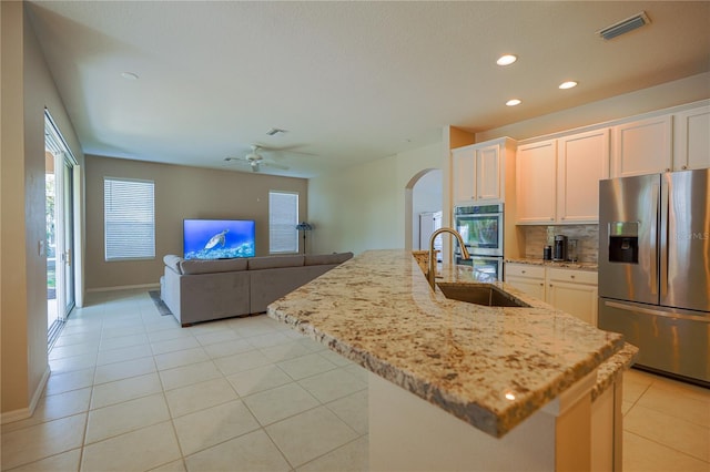 kitchen featuring stainless steel appliances, white cabinetry, a kitchen island with sink, and sink