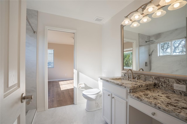 bathroom featuring tiled shower, vanity, toilet, and tile patterned flooring