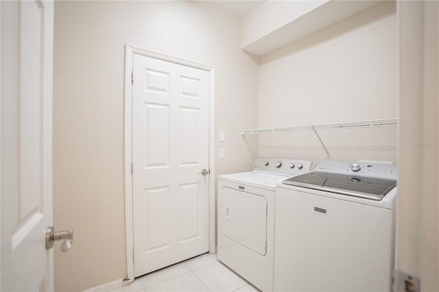 laundry room with washing machine and clothes dryer and light tile patterned floors