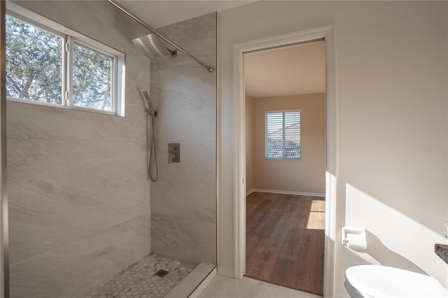 bathroom featuring toilet, wood-type flooring, and tiled shower