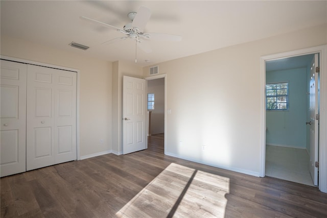 unfurnished bedroom featuring ceiling fan, a closet, and dark wood-type flooring