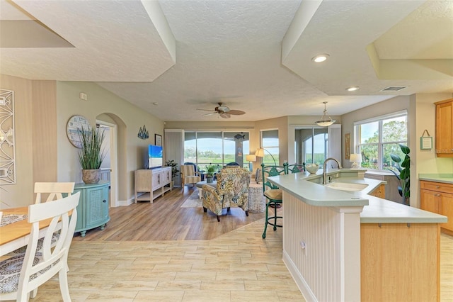 kitchen featuring a kitchen bar, ceiling fan, plenty of natural light, a kitchen island with sink, and sink