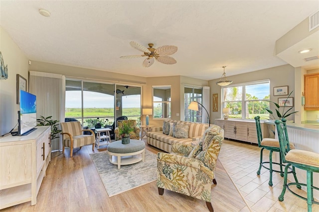 living room featuring ceiling fan, a textured ceiling, and light hardwood / wood-style floors