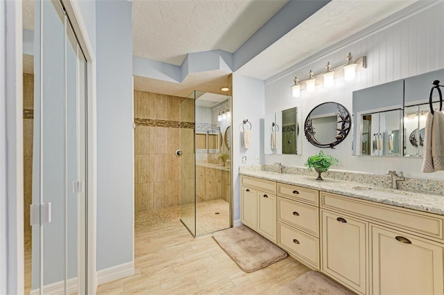 bathroom featuring hardwood / wood-style flooring, a textured ceiling, tiled shower, and vanity