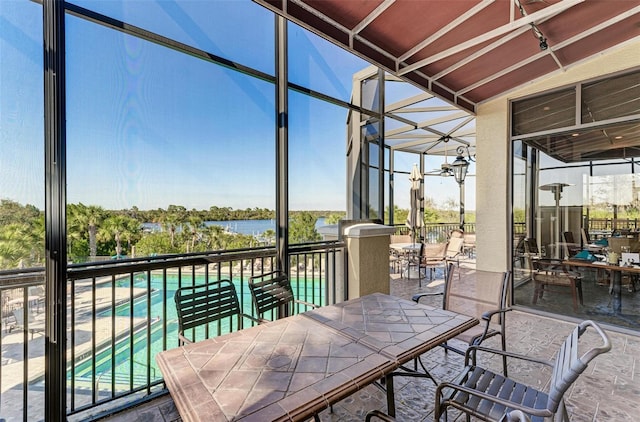 sunroom with a swimming pool, lofted ceiling, and a water view