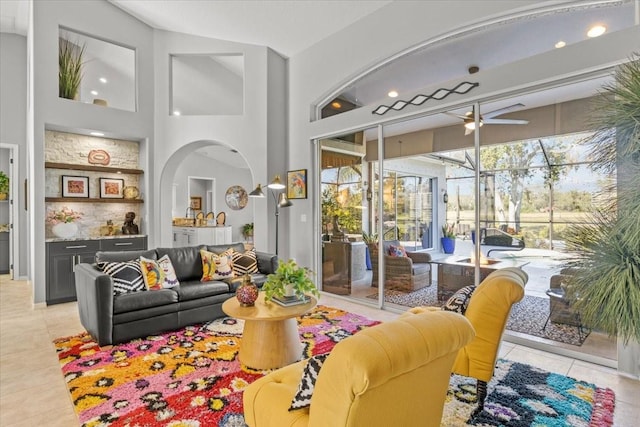 tiled living room with built in shelves, a towering ceiling, and ceiling fan