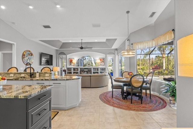 kitchen featuring ceiling fan, white cabinets, dark stone counters, decorative light fixtures, and light tile patterned flooring