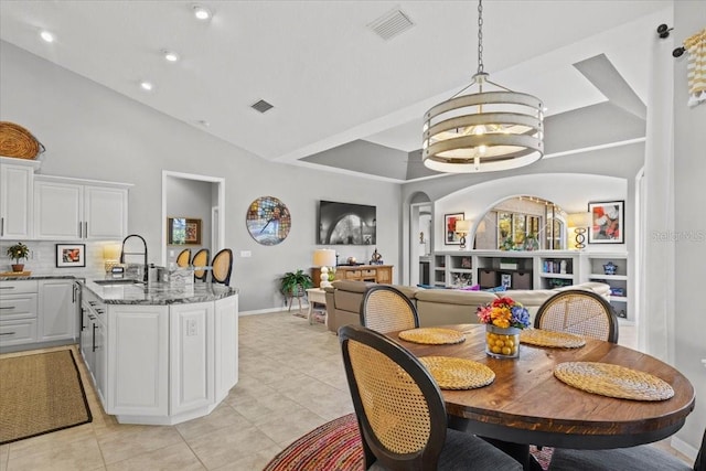 dining area featuring sink, light tile patterned floors, a notable chandelier, and high vaulted ceiling