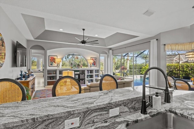 dining area featuring ceiling fan, a raised ceiling, and sink