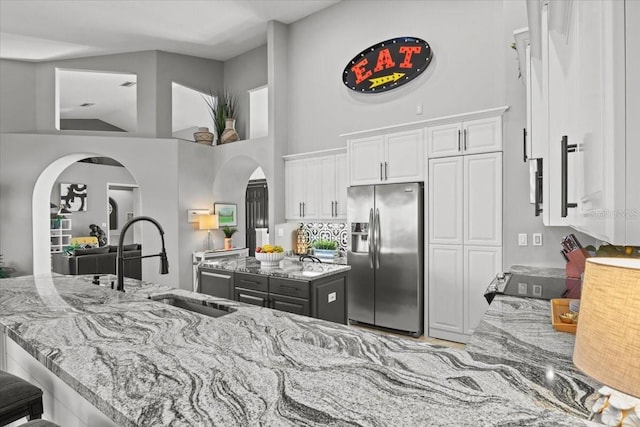 kitchen featuring white cabinetry, stainless steel fridge, and light stone countertops