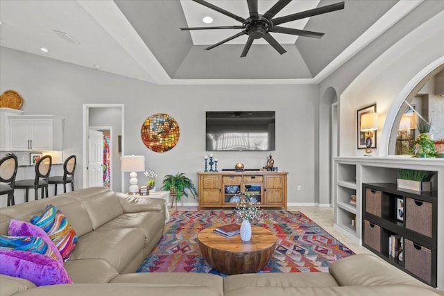 living room featuring built in shelves, ceiling fan, and a raised ceiling