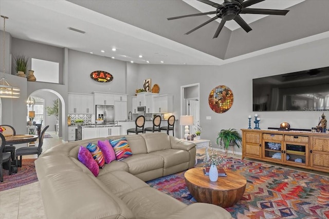 tiled living room with ceiling fan and a towering ceiling