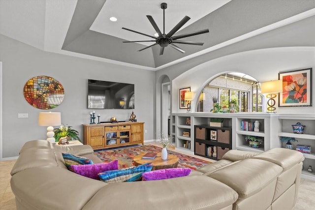 living room with built in shelves, a tray ceiling, and ceiling fan