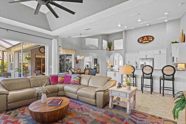 living room featuring ceiling fan, light tile patterned floors, and high vaulted ceiling