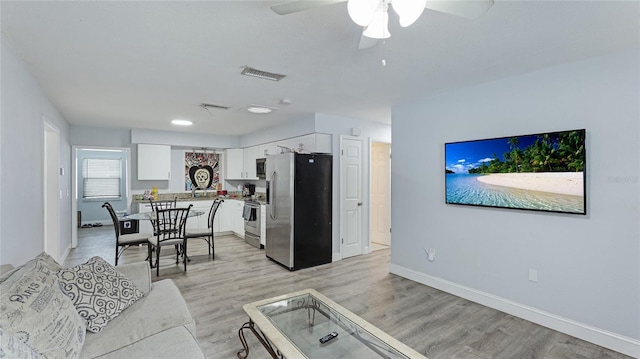 living room with light wood-type flooring and ceiling fan