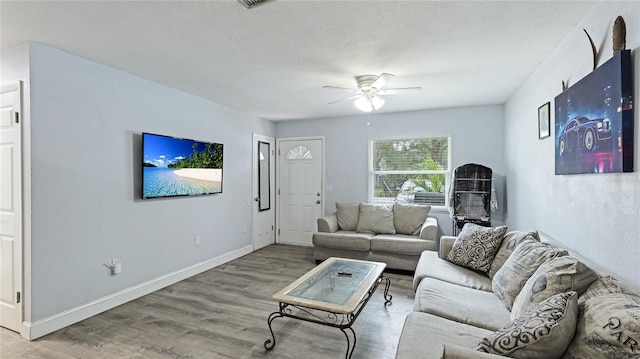 living room with hardwood / wood-style flooring, a textured ceiling, and ceiling fan