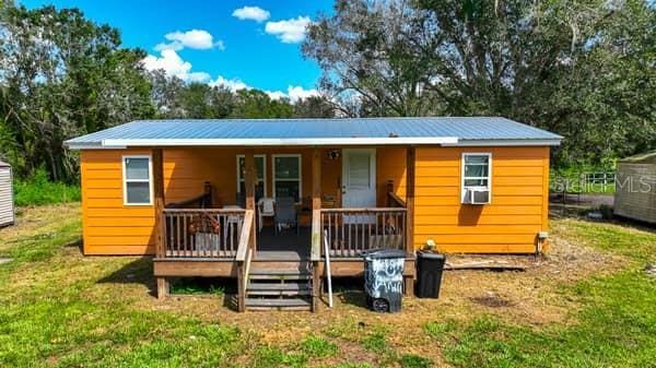 rear view of house with a porch, a yard, and cooling unit