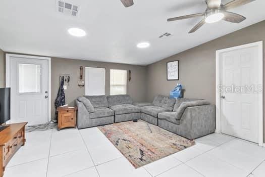 living room featuring light tile patterned floors, vaulted ceiling, and ceiling fan