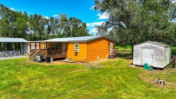 rear view of house featuring a lawn and a storage shed