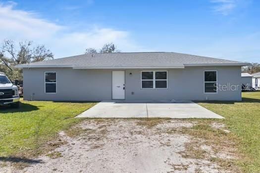 back of property featuring a patio and a lawn